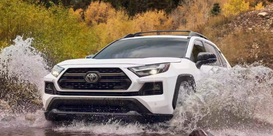 A white 2023 Toyota RAV4 small SUV is driving off-road.