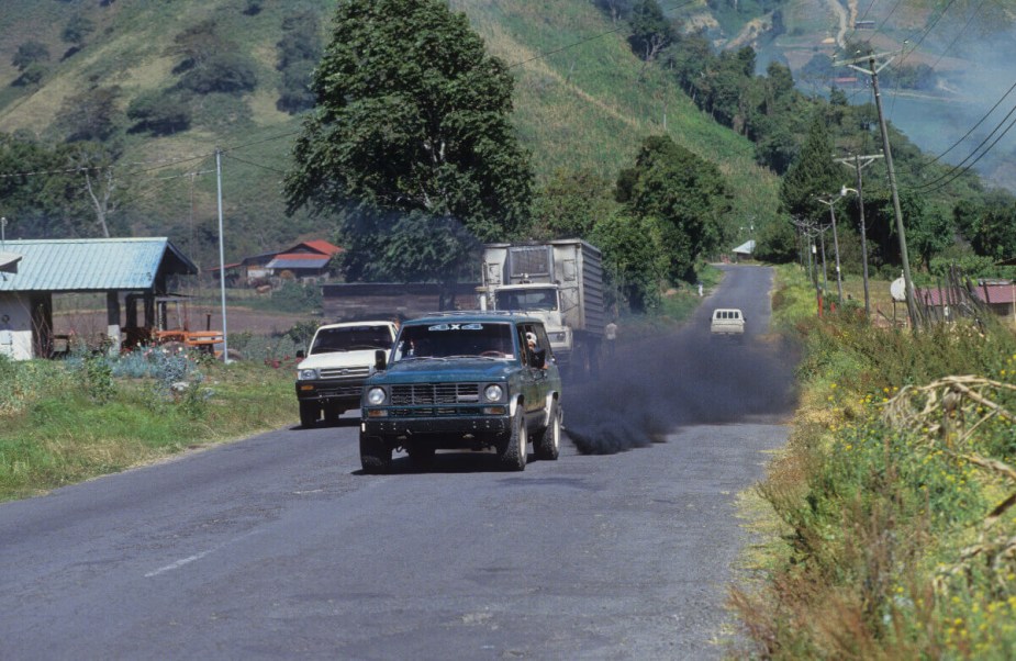 An SUV with black smoke coming from its exhaust.