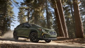 The updated 2024 Subaru Crosstrek in green drives through a forest.