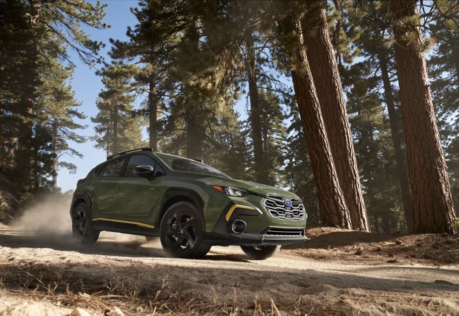 The updated 2024 Subaru Crosstrek in green drives through a forest. 