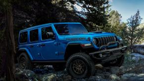 A blue Wrangler Rubicon 392 sitting atop rocks in a forest.