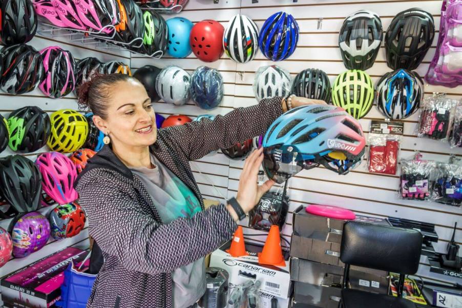 A bike shop employee showing off bike helmet features to a customer in Bogota, Colombia, Engativa