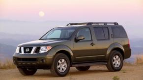 A dark green 2006 Nissan Pathfinder midsize SUV model parked on a dry desert plain