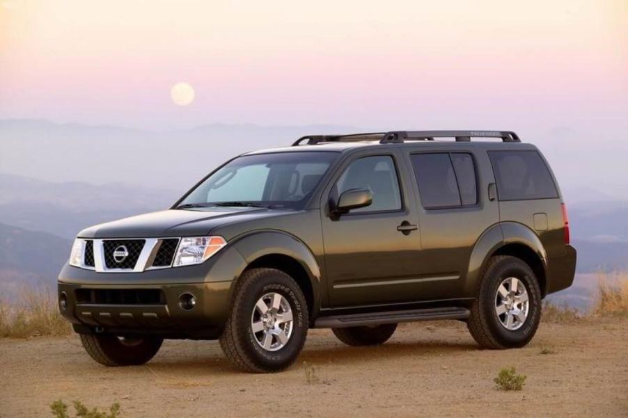 A dark green 2006 Nissan Pathfinder midsize SUV model parked on a dry desert plain