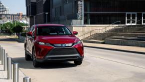 A red 2022 Toyota Venza midsize hybrid SUV model parked near a line of metal bollards