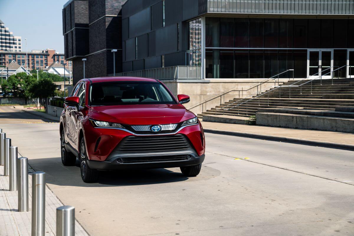 A red 2022 Toyota Venza midsize hybrid SUV model parked near a line of metal bollards