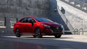 A red 2023 Nissan Versa subcompact sedan model parked on a concrete alcove