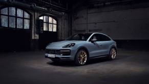 A steel blue Porsche Cayenne Turbo GT midsize luxury crossover SUV model parked in an empty warehouse garage