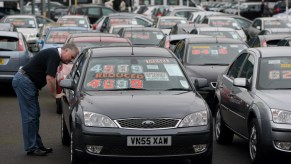 A used car shoppers looks at used cars on a lot