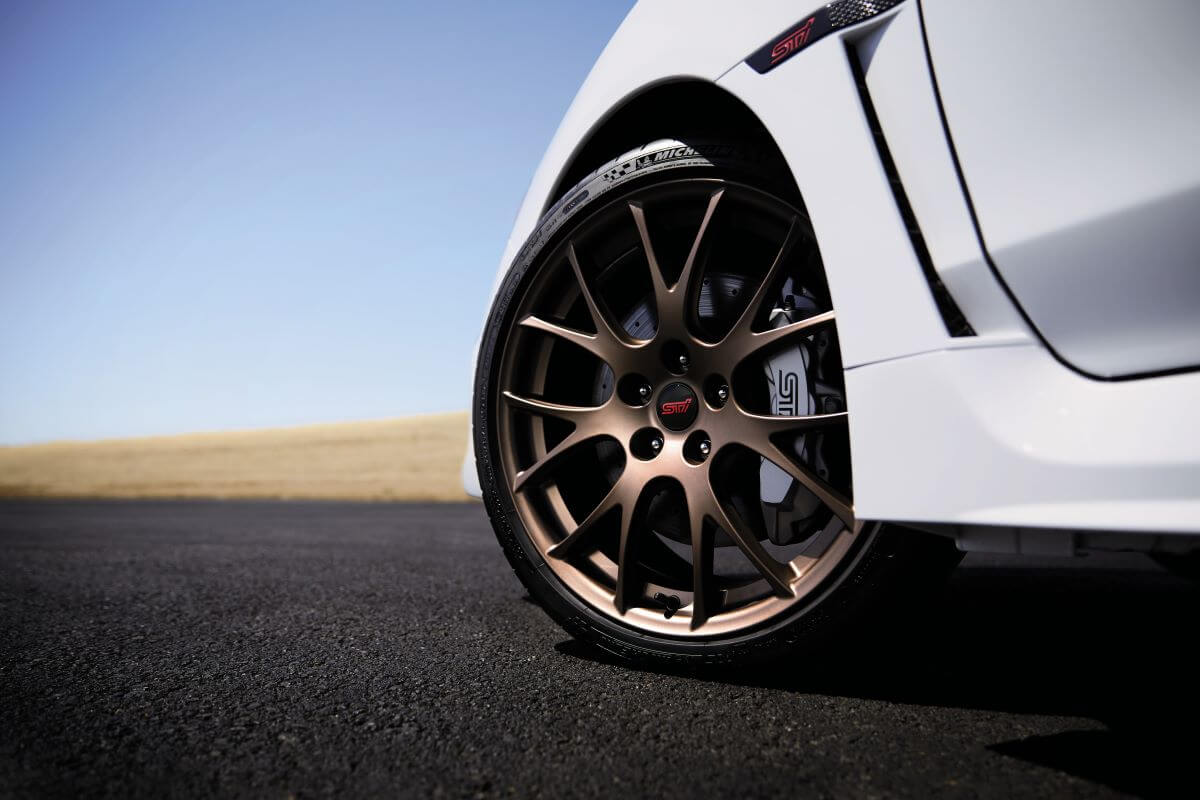 A closeup of the wheel and brake calipers on a white 2020 Subaru WRX STI