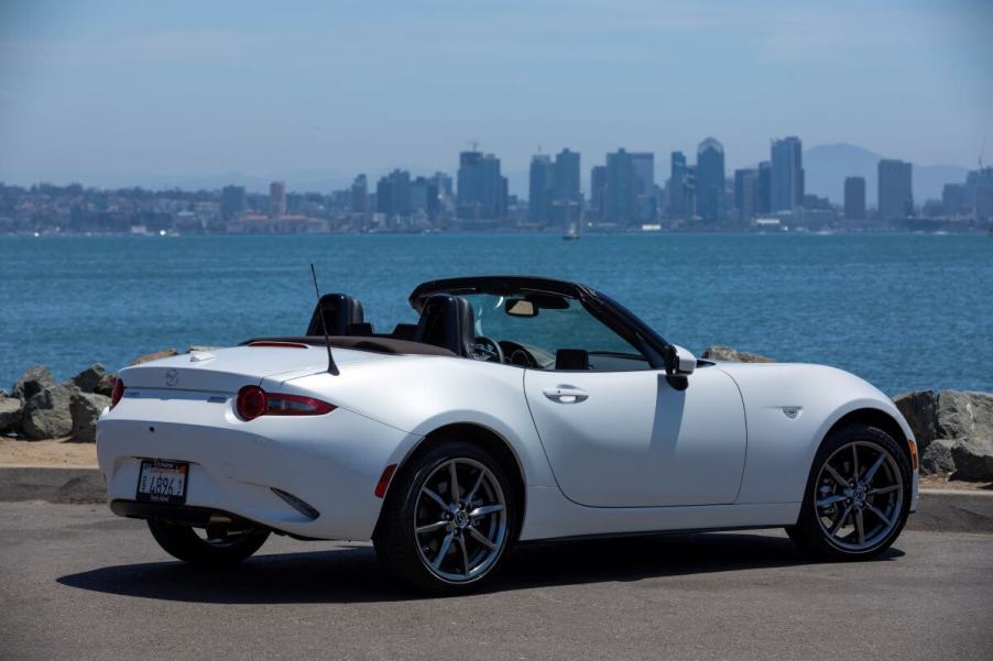 A white 2019 Mazda MX-5 Miata convertible coupe sports car model parked near a large body of water