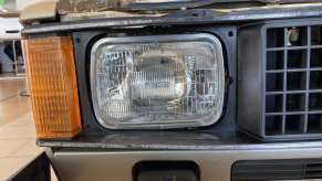 Closeup of the square headlight, grille, and turn signal of a Volkswagen Rabbit compact pickup truck.