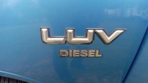 The LUV and Diesel badges on the blue front fender of a compact Chevrolet pickup truck built by Isuzu for 1982.