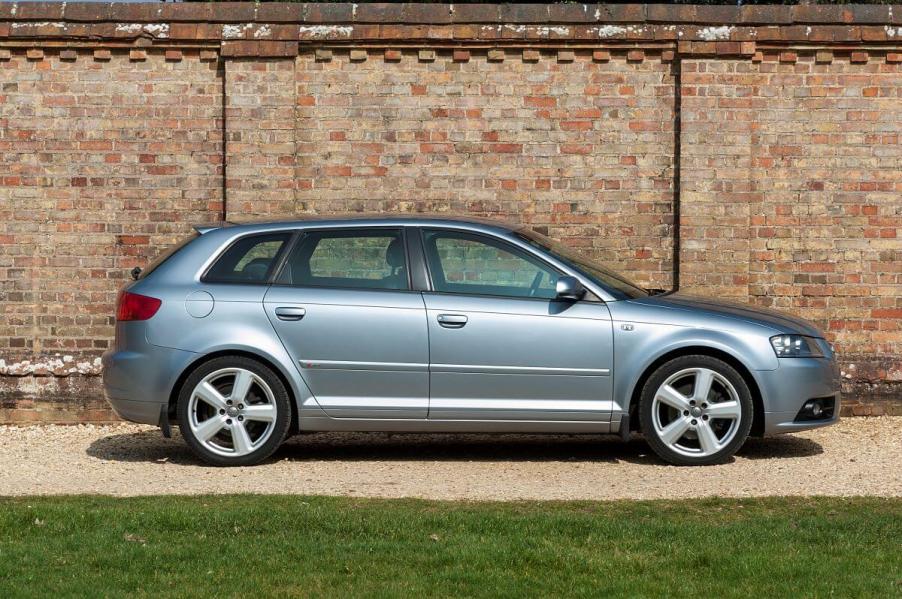 An exterior side profile of a blue 2006 Audi A3 Sportback S-Line hatchback model parked in front of a brick wall