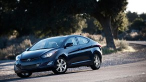 A blue 2013 Hyunda Elantra model corners on a country road.