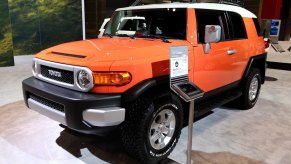 An orange 2013 FJ Cruiser parked in doors on display.