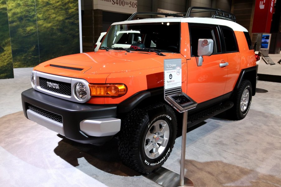 An orange 2013 FJ Cruiser parked in doors on display.