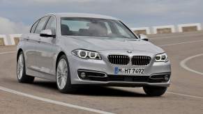 A silver 2014 BMW 5 Series driving down a road.