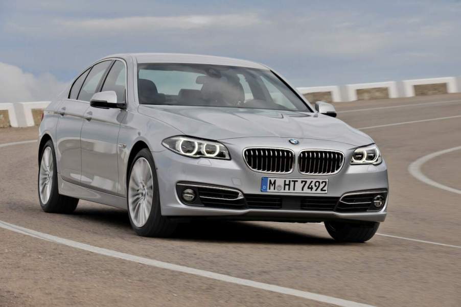 A silver 2014 BMW 5 Series driving down a road.