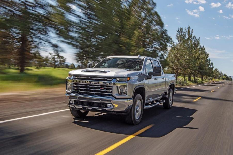 A silver-gray 2021 Chevrolet Chevy Silverado 2500 HD heavy-duty pickup truck model driving down a rural highway