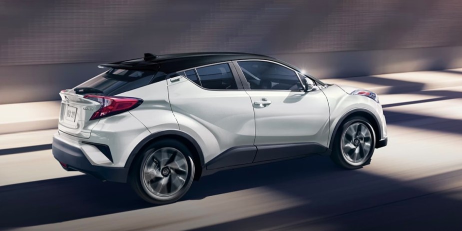 A white 2022 Toyota C-HR subcompact SUV is driving on the road. 