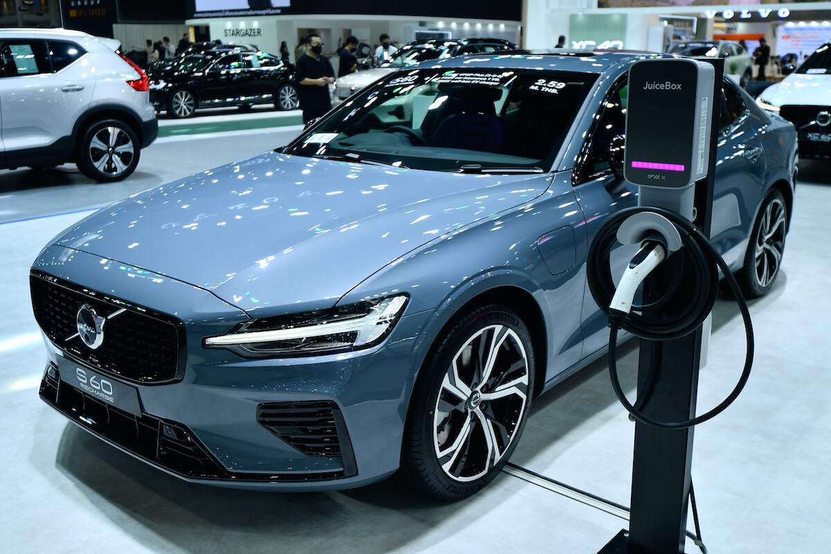 A light blue 2022 Volvo S60 next to a charger.