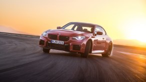 An orange 2023 BMW M2 slides around a track.