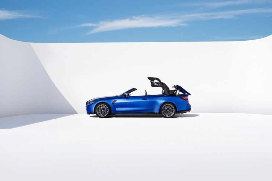 A BMW M4 Competition Convertible drops its sports car top against a white background.