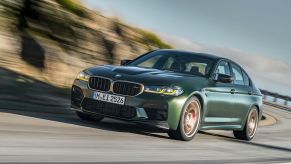 A front view of the 2023 BMW M5 driving down a road.