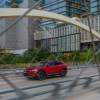 A red 2023 Buick Envision driving down the highway in a city with buildings in the background.