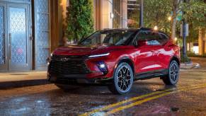 A red 2023 Chevrolet Blazer parked on the ride of a city street.