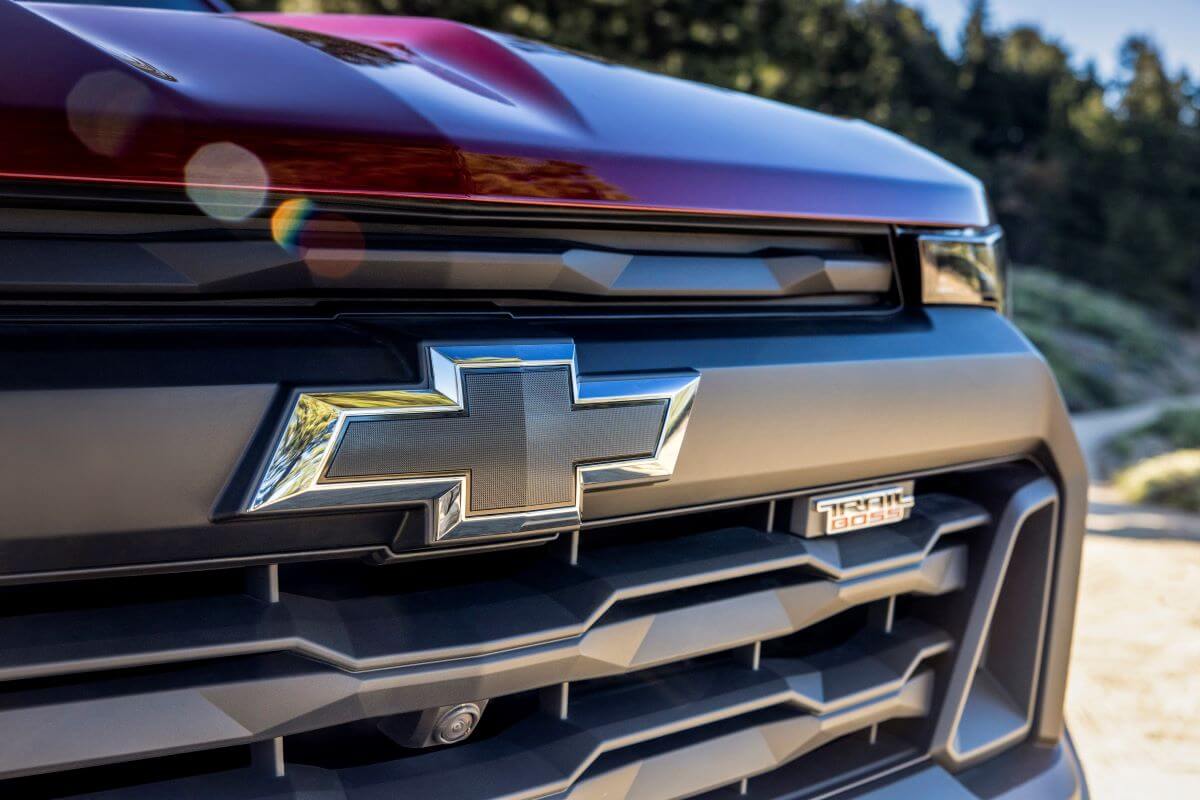 A closeup shot of the grille emblem and Trail Boss badging of a red 2023 Chevy Colorado Trail Boss