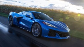 A bright blue Chevy Corvette Z06 supercar from the C8 generation blasts down a back road.