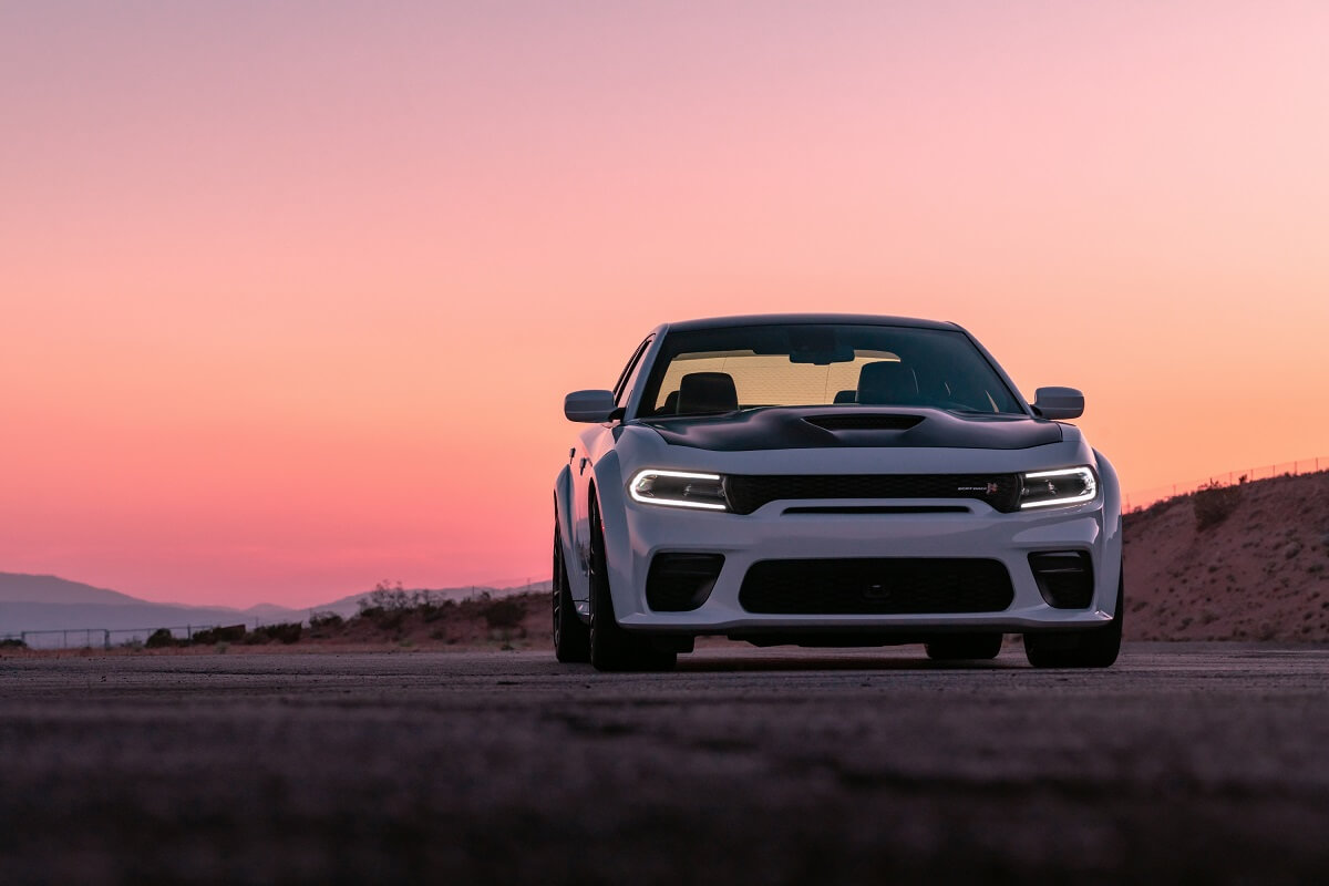 A 2023 Dodge Charger R/T Scat Pack Widebody parks on a dirt road at sunset.