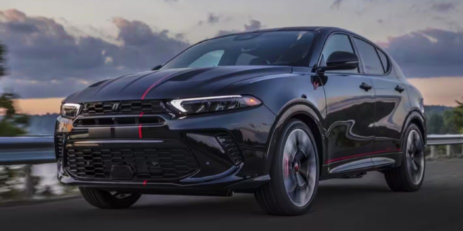 A black 2023 Dodge Hornet small SUV is driving on the road. 