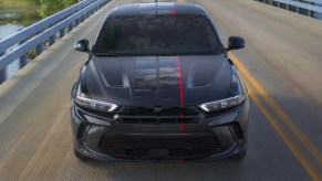 A black 2023 Dodge Hornet small SUV is driving on the road.