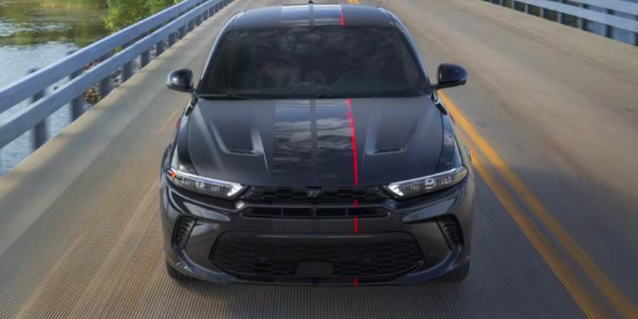 A black 2023 Dodge Hornet small SUV is driving on the road. 