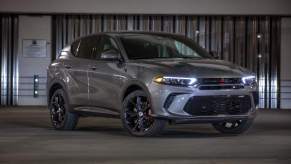 A grey 2023 Dodge Hornet parked in front of a metal wall.