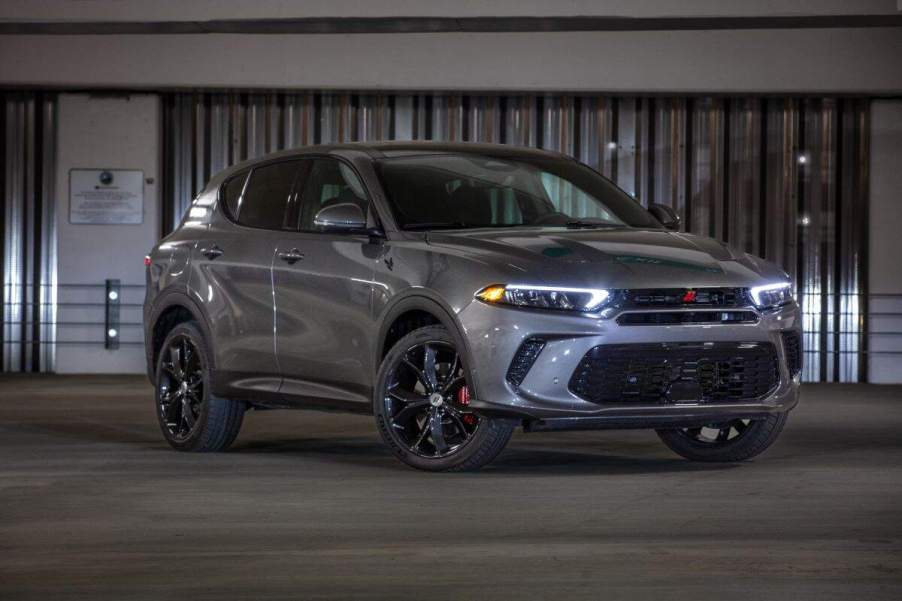 A grey 2023 Dodge Hornet parked in front of a metal wall.