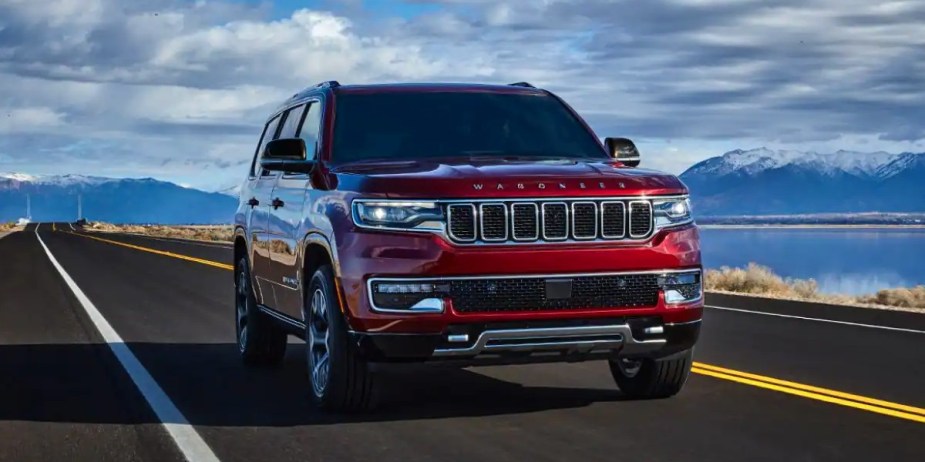 A red Jeep Wagoneer full-size SUV is driving on the road. 