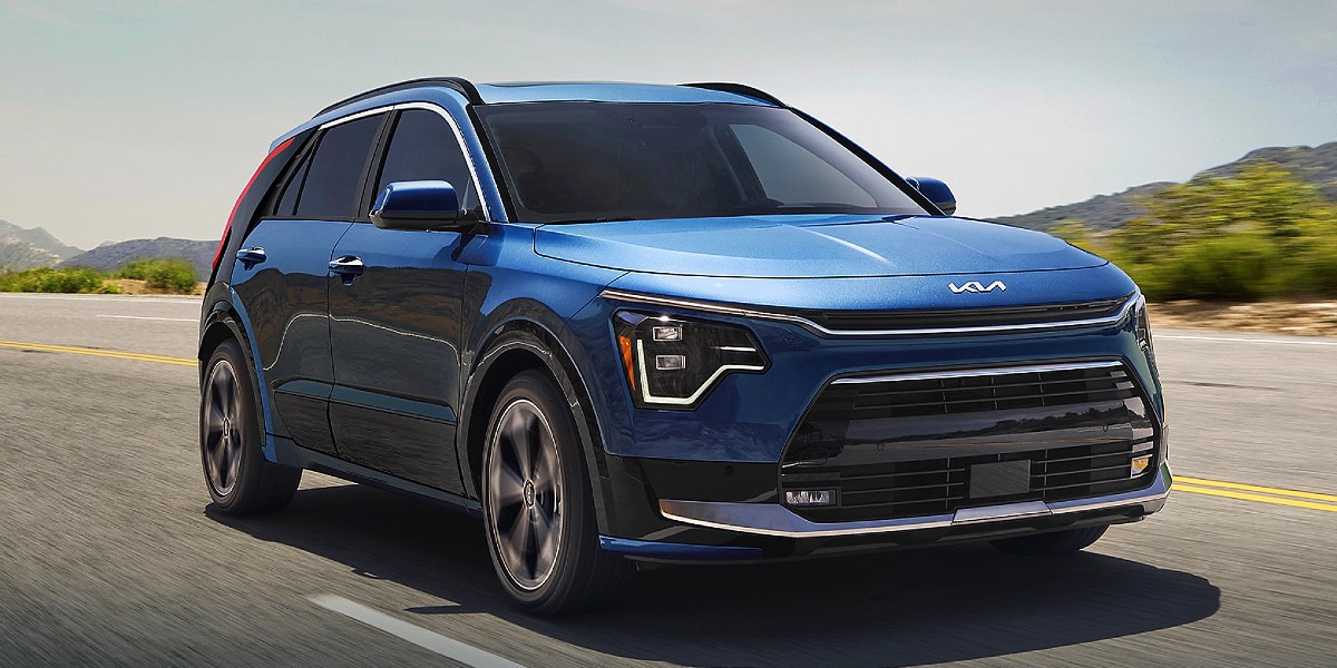 A blue 2023 Kia Niro Plug-In Hybrid subcompact PHEV SUV is driving on the road.