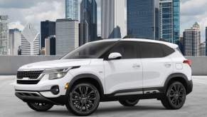 A white 2023 Kia Seltos parked in front of a skyline.