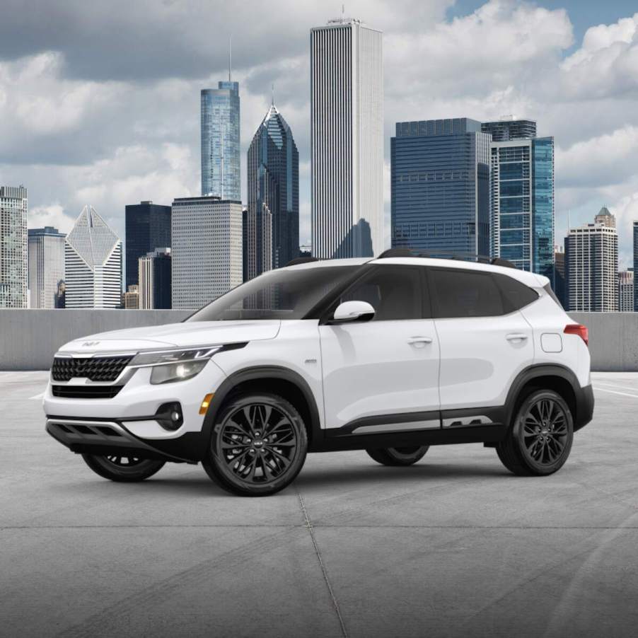 A white 2023 Kia Seltos parked in front of a skyline.