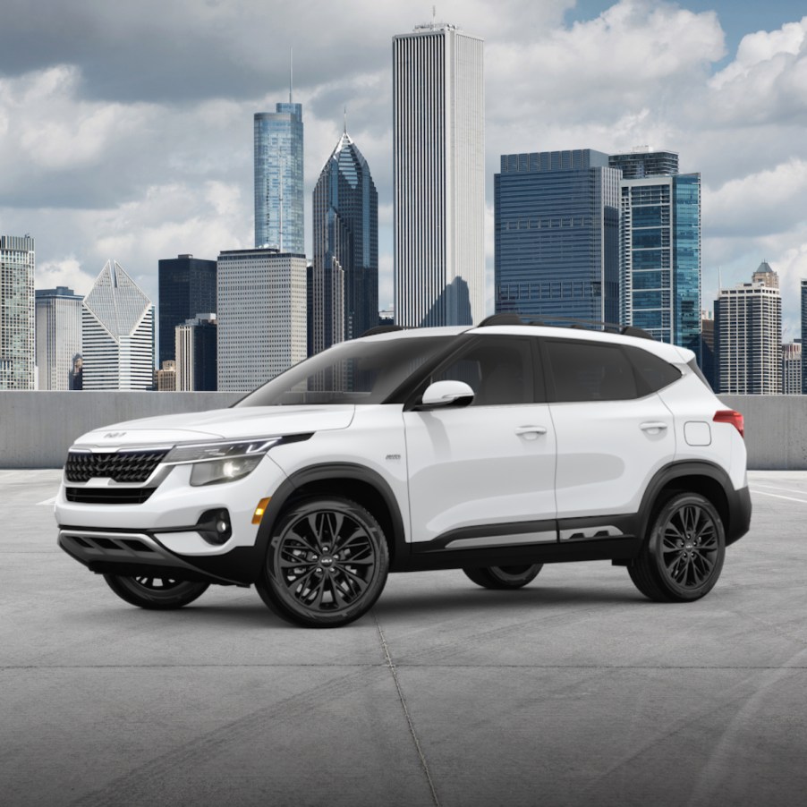 A white 2023 Kia Seltos parked in front of a city skyline.