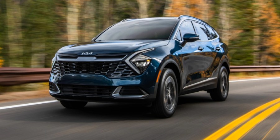 A blue 2023 Kia Sportage Hybrid is driving on the road.