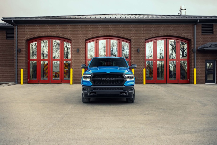 Grille of a blue 2023 Ram 1500 pickup truck parked in front of a fire station.