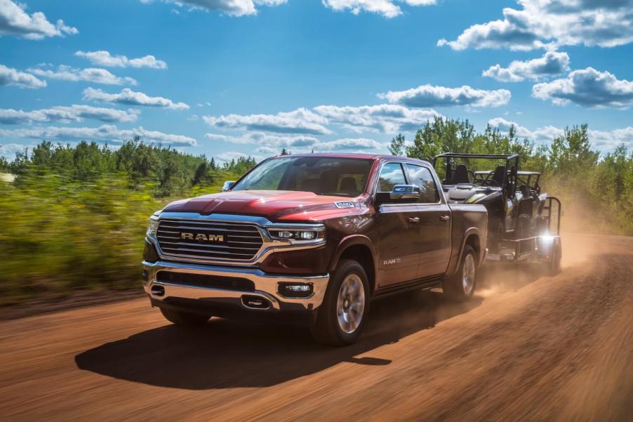 Red 2023 Ram 1500 pickup truck pulling a trailer.