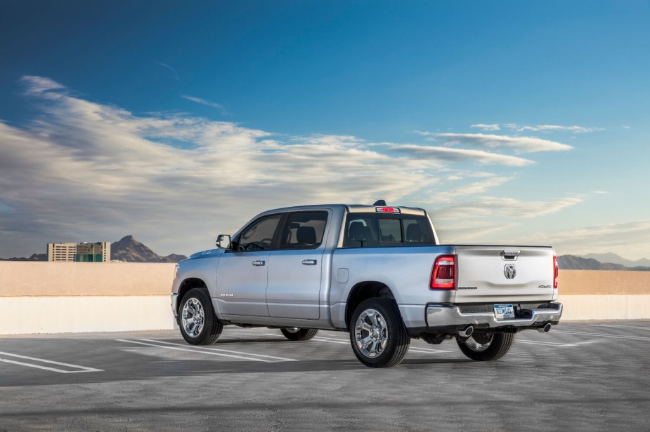 The back of a silver Ram 1500 parking truck on the top of a parking garage, clouds visible in the background.