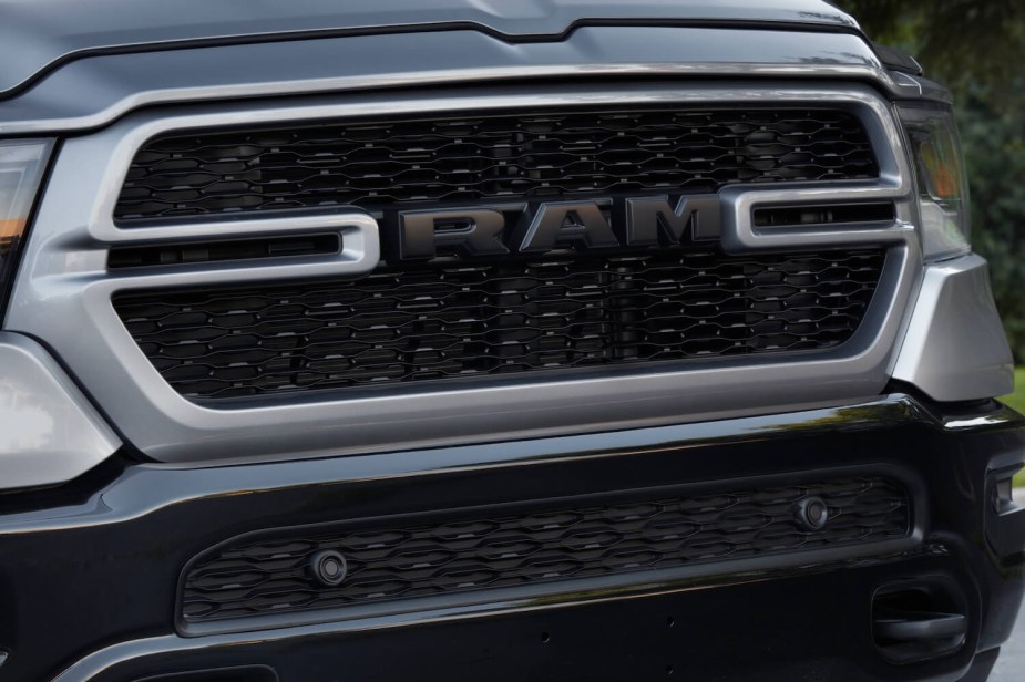 The grille of a silver Ram 1500 pickup truck with black badges.