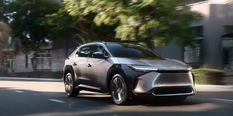 A gray 2023 Toyota bZ4X small electric SUV is driving on the road. 